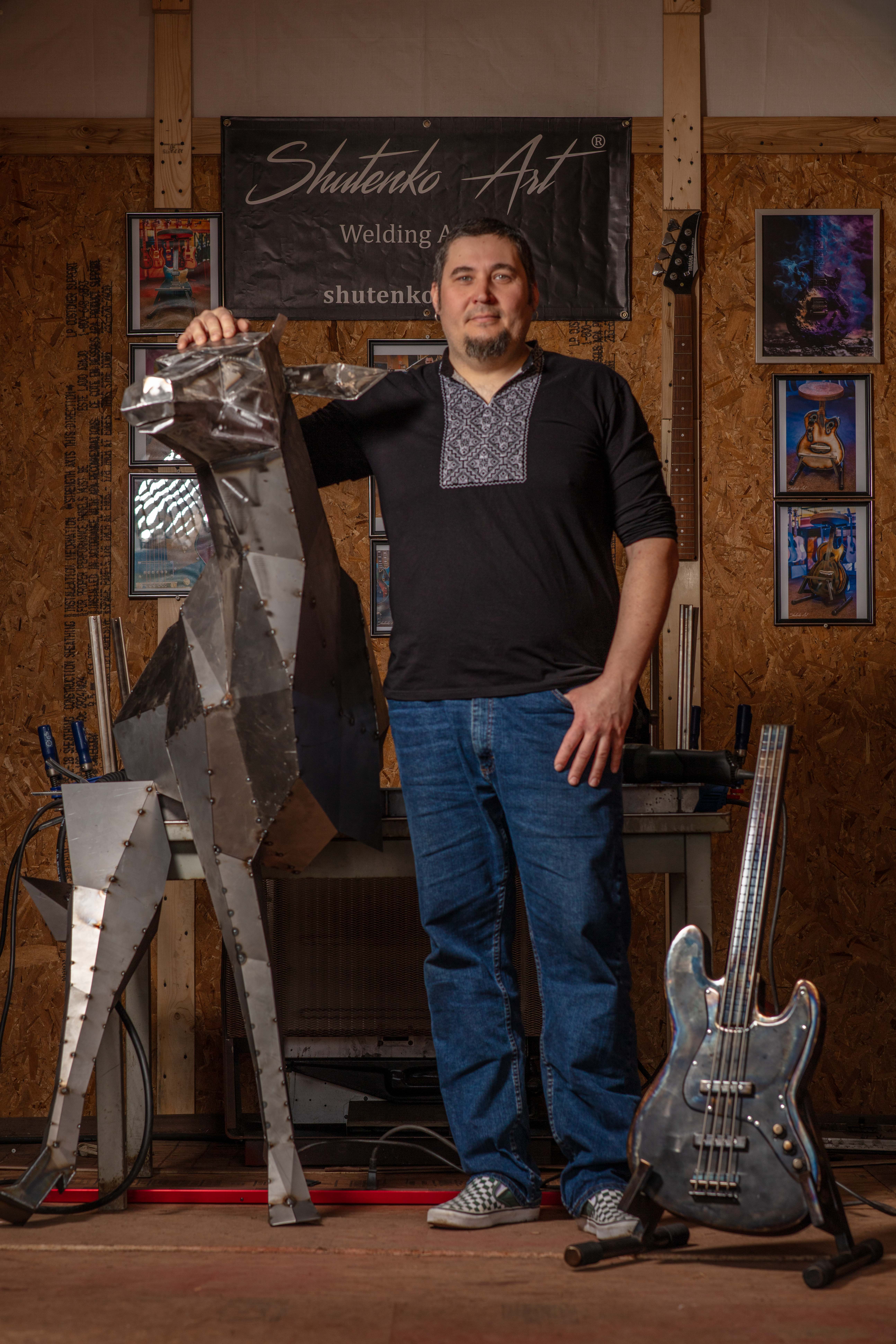 Andriy Shutenko beside a geometric metal sculpture